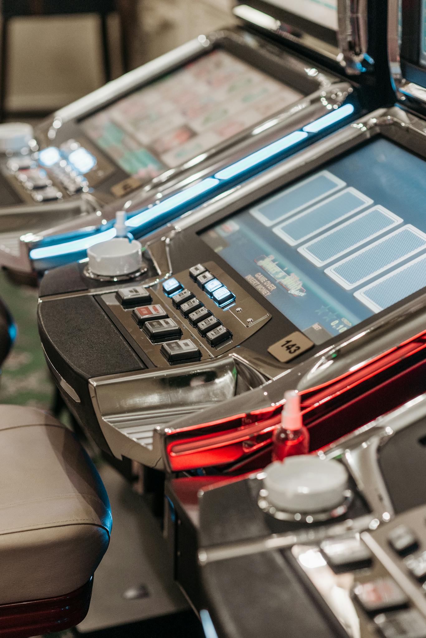 Detailed view of illuminated slot machines in a casino, showcasing vibrant screens and controls.